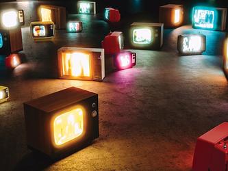 image of many powered on different crt televisions laying on the floor